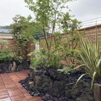いろは苑が横浜で作った溶岩石の花壇とウッドフェンスのあるモダンな屋上庭園